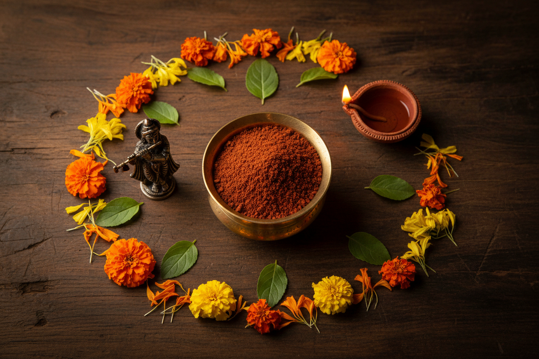 Braj Raj, the reddish sacred soil of Vrindavan, in a brass bowl encircled by marigolds and Tulsi leaves beside a small Krishna figure and a lit diya